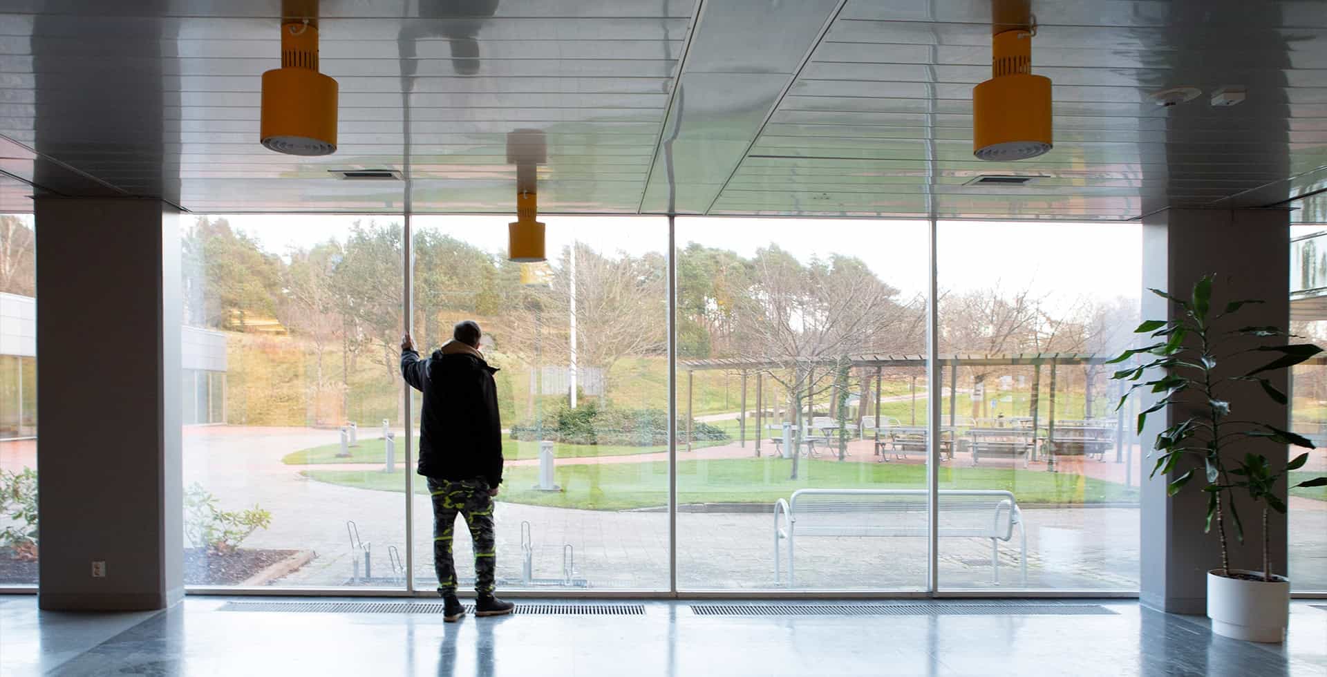 Niklas står ett stort rum och blickar ut genom stora fönster.