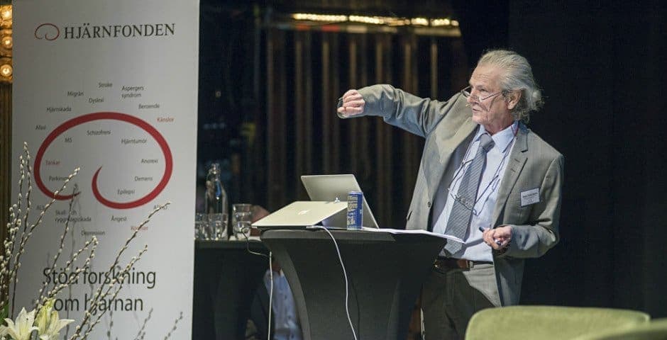 Mats Fredrikson talar i en mikrofon och illustrerar med sin hand.