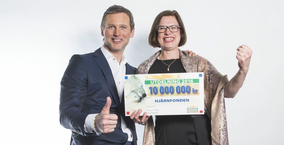 Porträtt av Rickard Sjöberg från Postkodlotteriet och Anna Hemlin som håller i en check på 10 miljoner kronor.