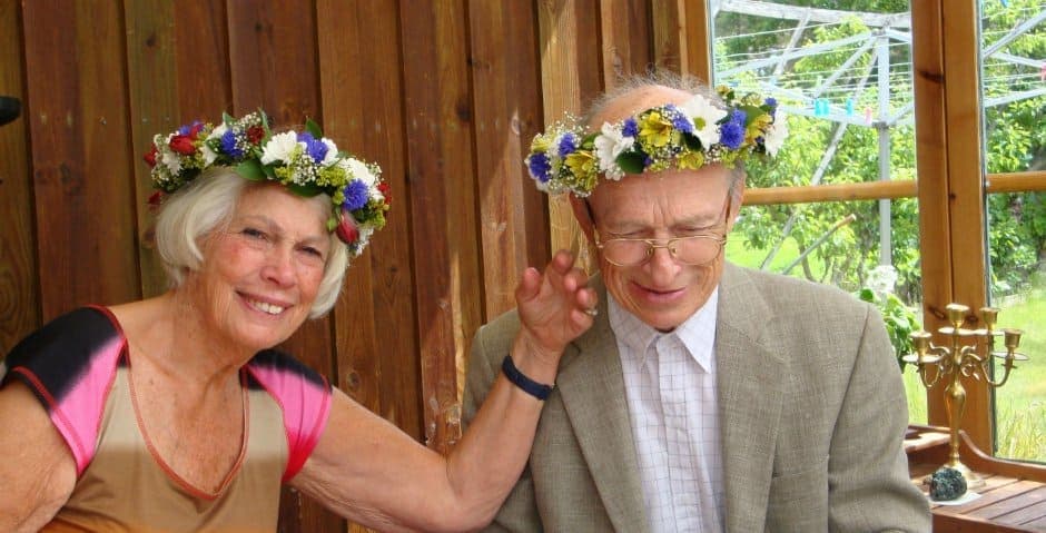 Birgitta och Lars Hemlin sitter med midsommarkransar på huvudet.