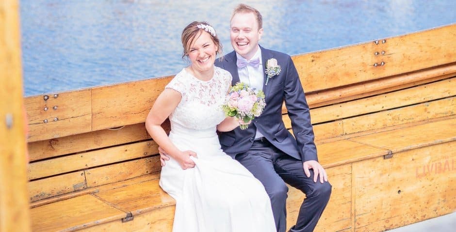 Bröllopsbild av Marie och Johannes som sitter vid vattnet.