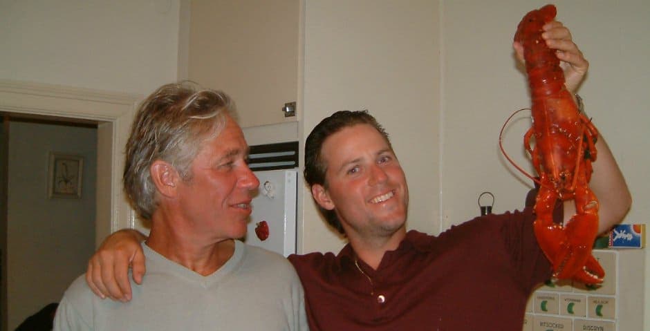 Tobias Hildebrand står med armen runt sin pappa och håller i en stor kräfta.