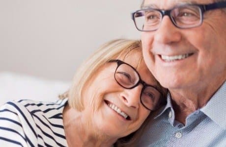 Ett äldre par kramar om varandra och ler glatt.