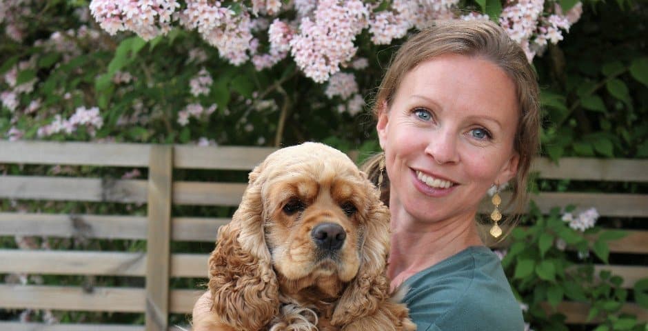 Porträtt av Emma Holmgren som håller en hund i sin famn.