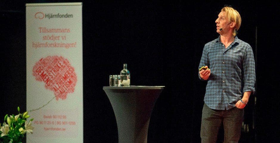 Anders Hansen står på scen och talar i en mikrofon.