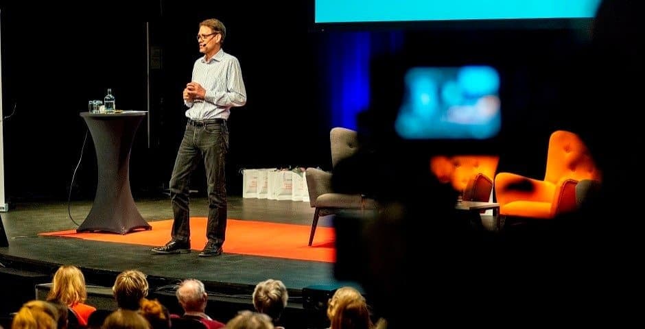 Martin Ingvar står på en scen framför publik och talar.