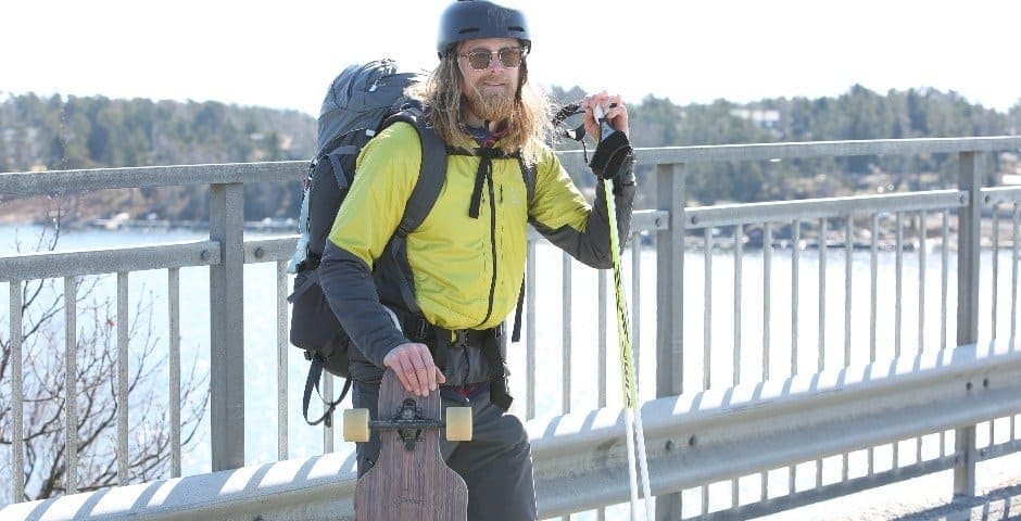 Erik Sander står med sin longboard i handen på en bro.