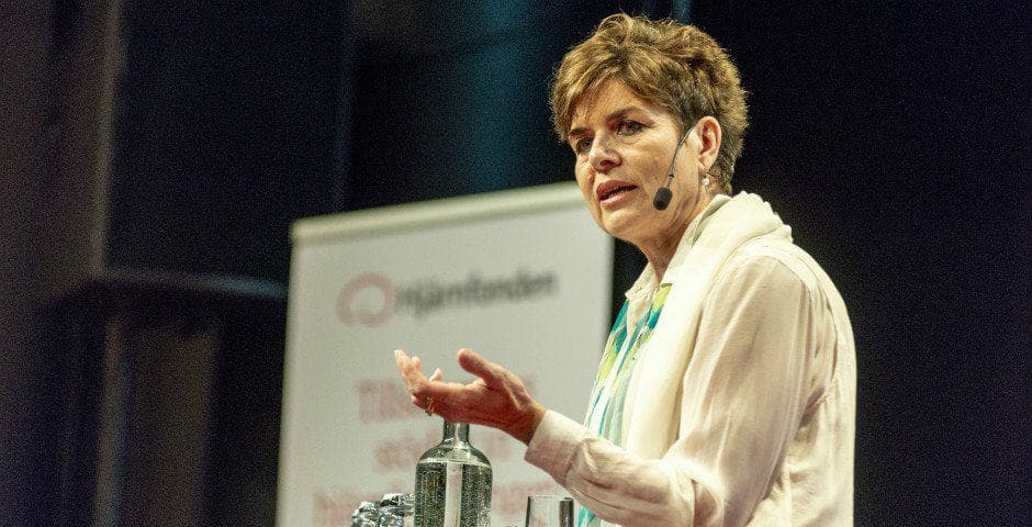 Ulla Karin står på en scen och talar i en mikrofon.