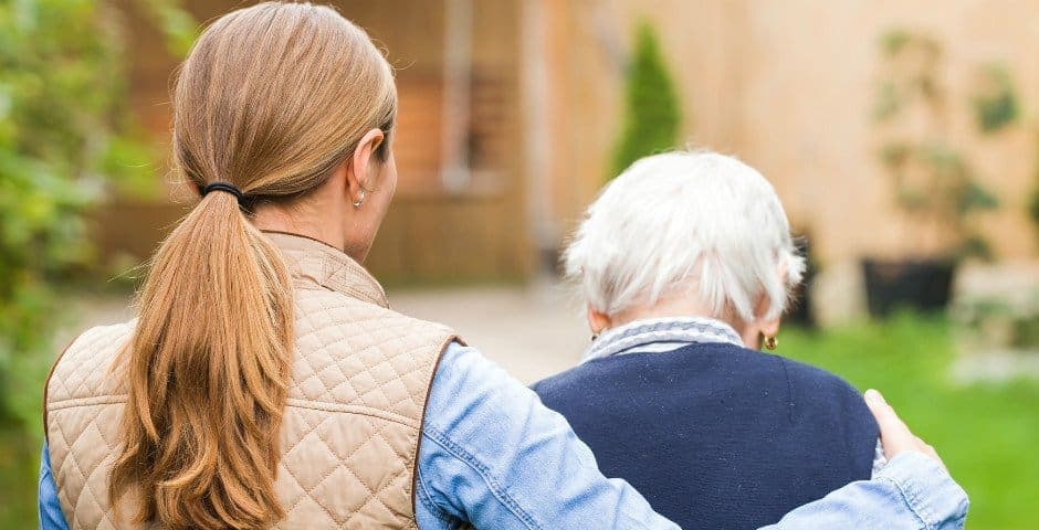 Kvinna går och håller om en äldre dam.