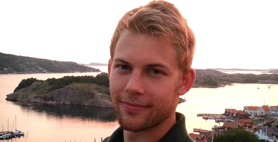 Porträtt av Niclas König mot en bakgrund med öar och vatten.