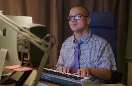 Alexander spelar på ett elektronisk piano vid sin dator.