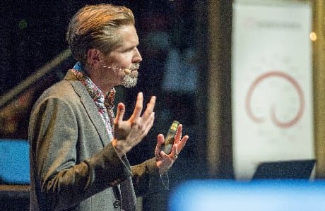 Sven Bölte står på en scen och talar.
