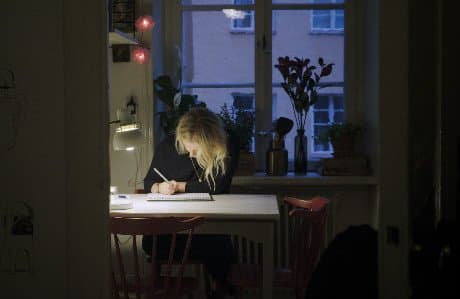 Edith tecknar på ett papper vid ett bord.