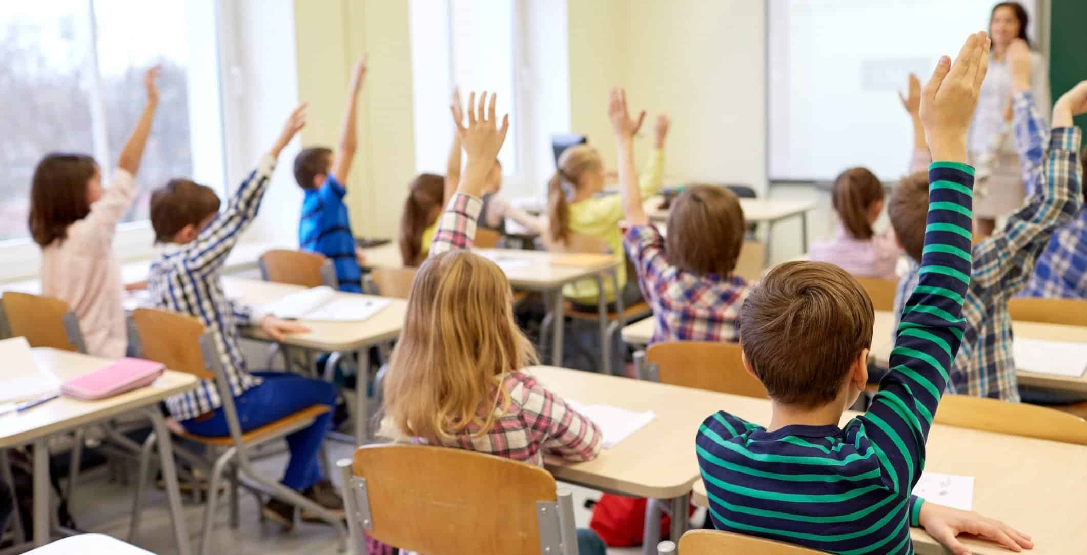Ett klassrum med barn som räcker upp händerna.