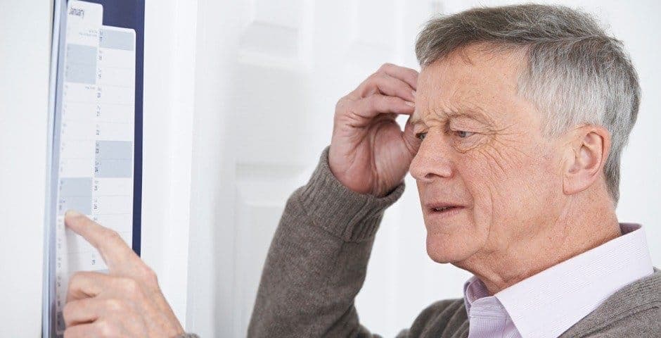 Äldre man kliar sig på huvudet och har fingret på en kalender.