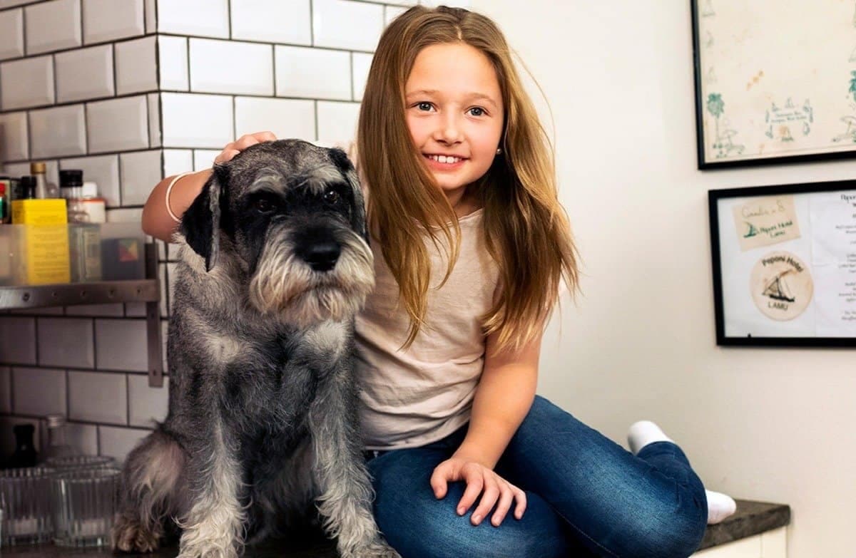 Liten flicka sitter med en hund på en köksbänk.