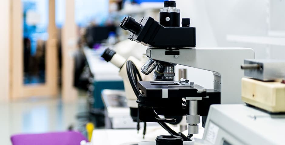 Mikroskop på ett bord i ett labb.