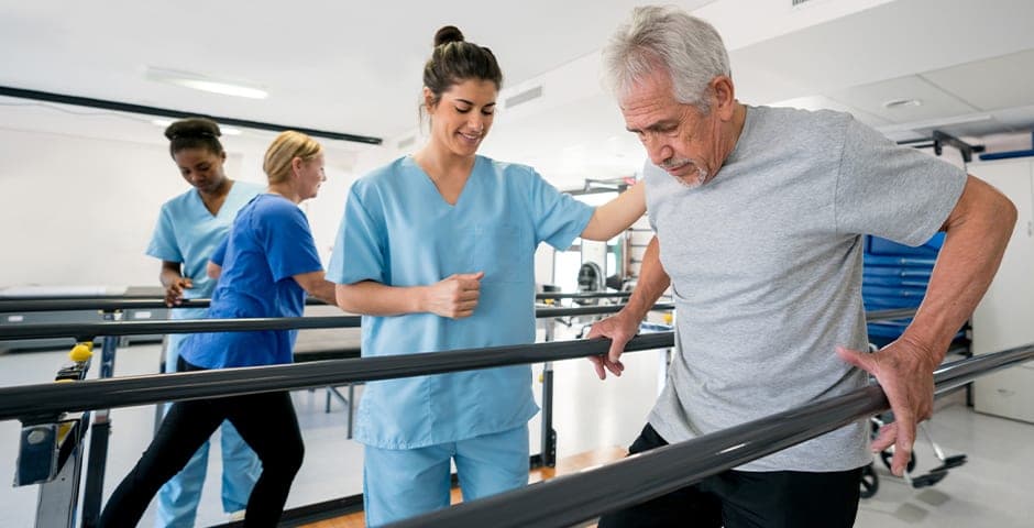 En man håller sig i två räcken och tränar på att gå.