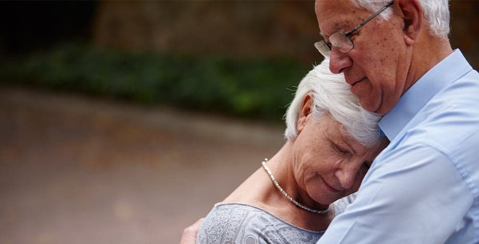 Ett äldre par som kramar om varandra.