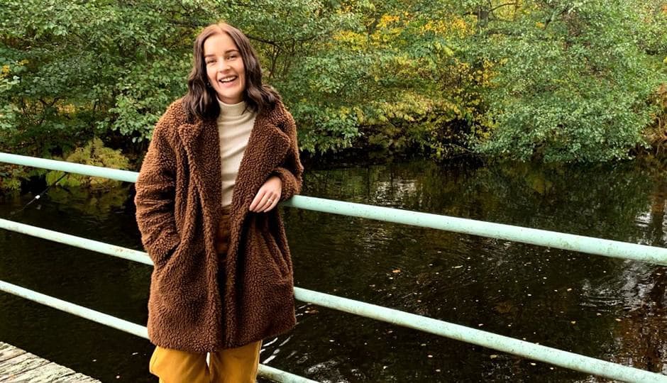 Nikki Kjellsson står på en bro över en å. I bakgrunden vackra höstlöv.