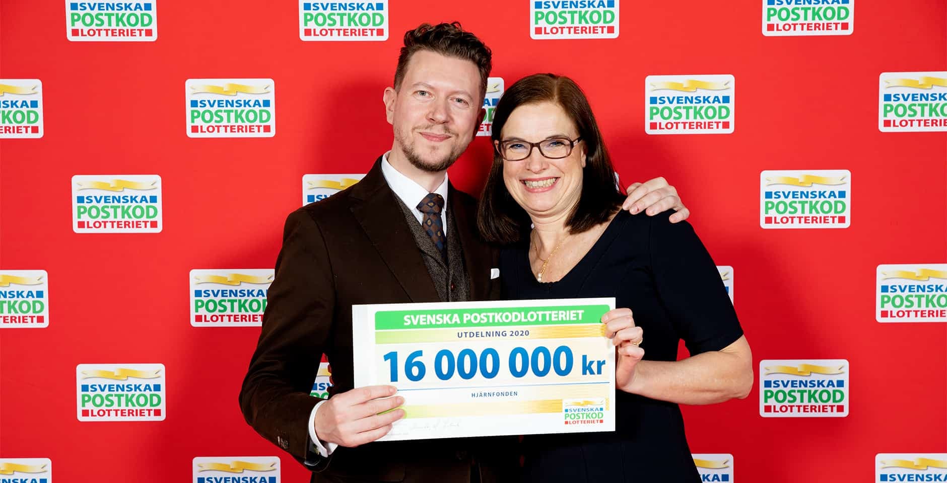 Tommy Sollén och Anna Hemlin står med en check på 16 miljoner mot en bakgrund med postkodlotteriets logotyp.