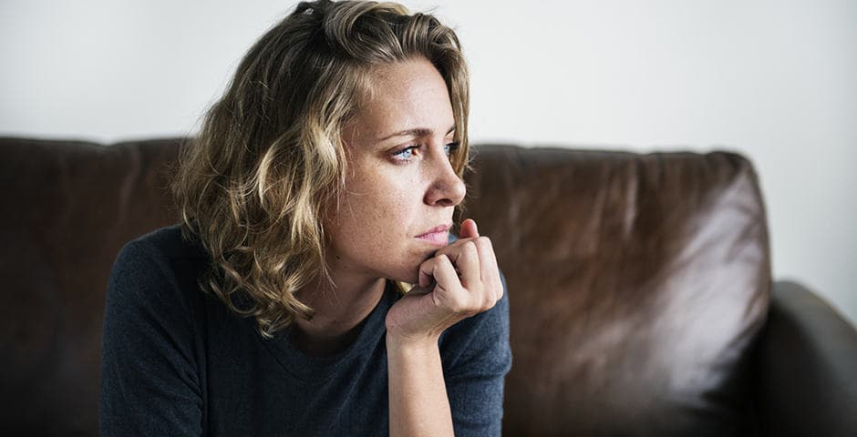 Kvinna som lutar hakan mot handen och ser fundersam ut.