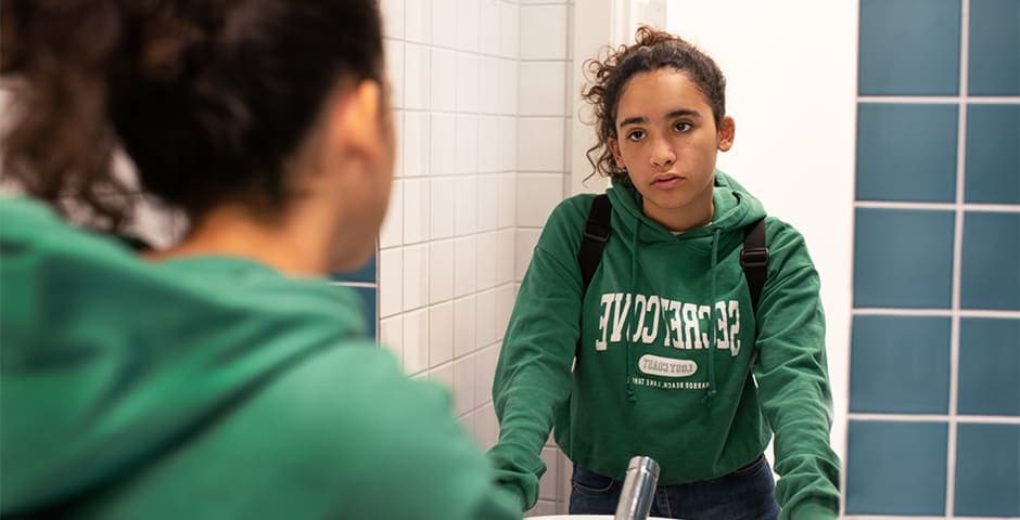 Orolig flicka tittar sig i spegeln.