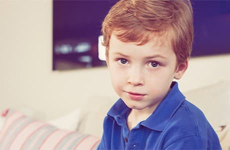 Pojke i 7-års åldern sitter i en soffa.