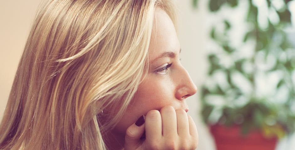 Tonårsflicka sitter med huvudet i handen.