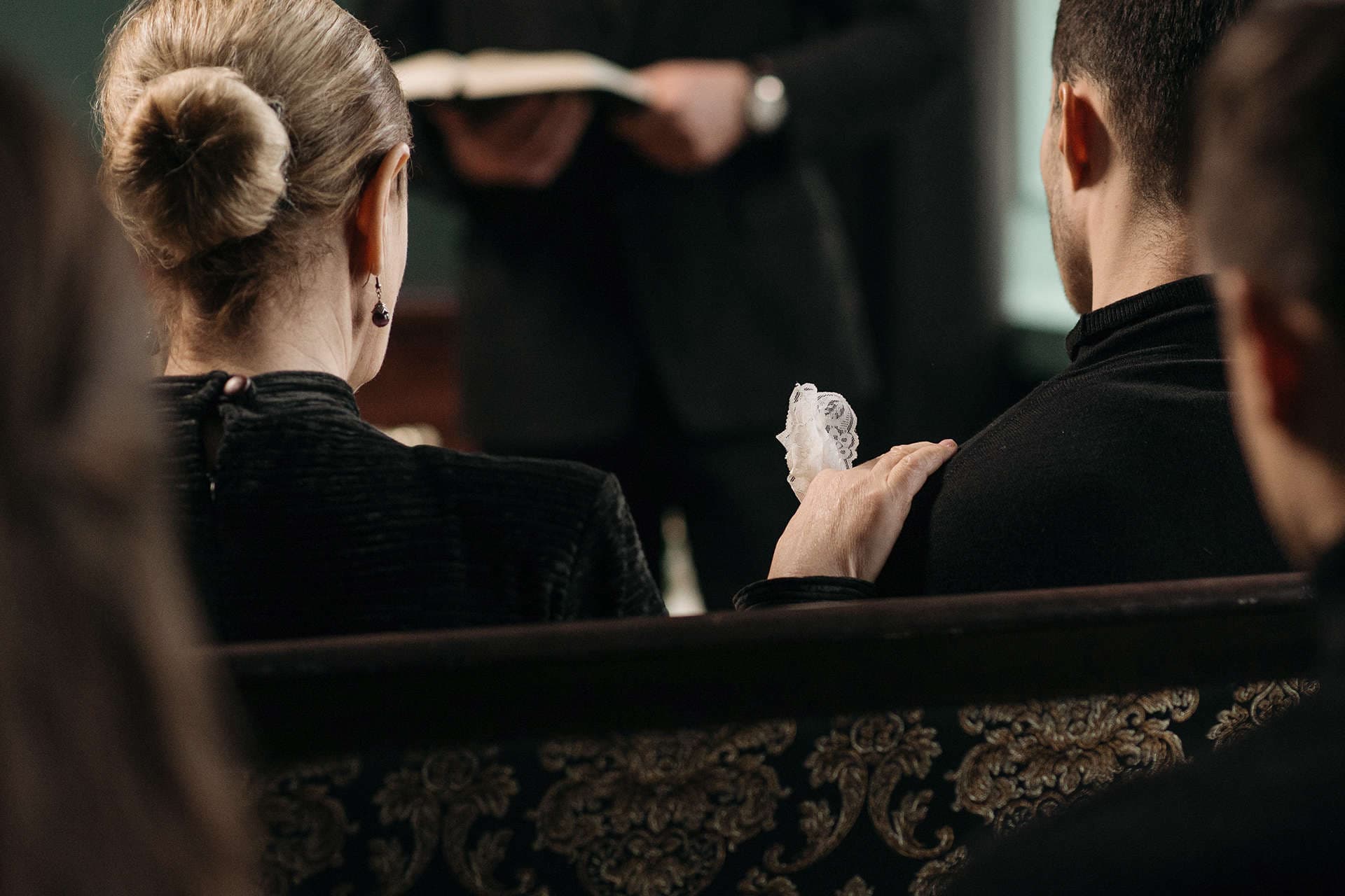 En man och en kvinna bakifrån som sitter ner i en kyrka.