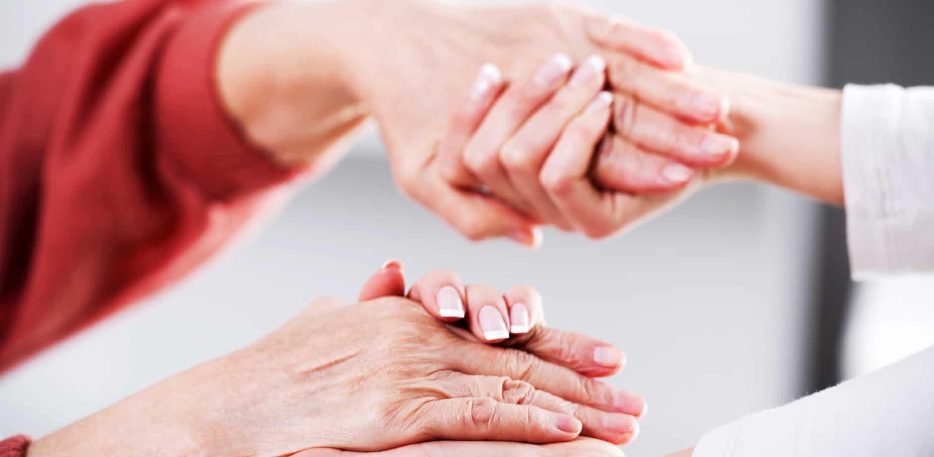 En yngre person håller i en äldre persons händer.