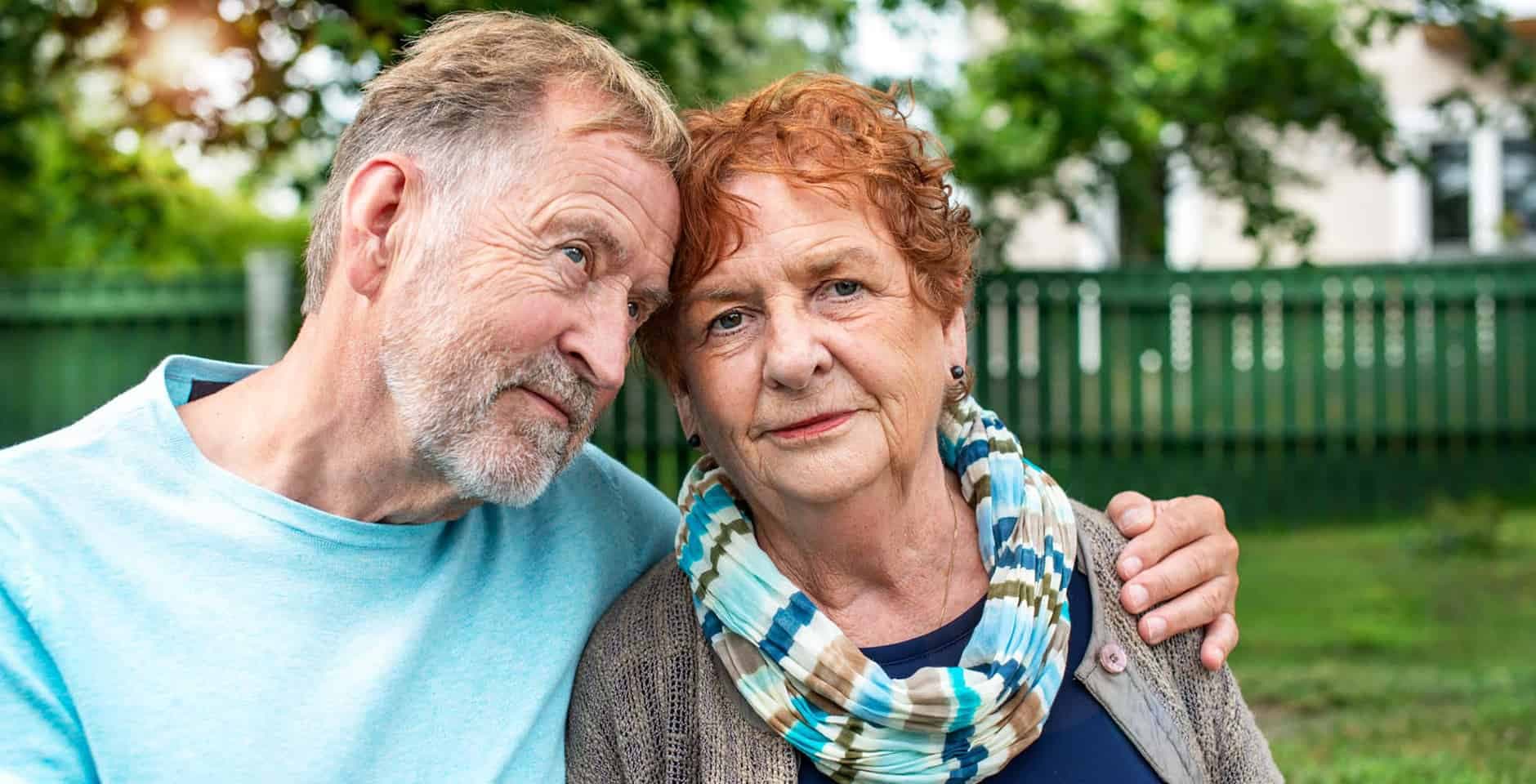 Ett äldre par står ute och mannen håller om kvinnan.