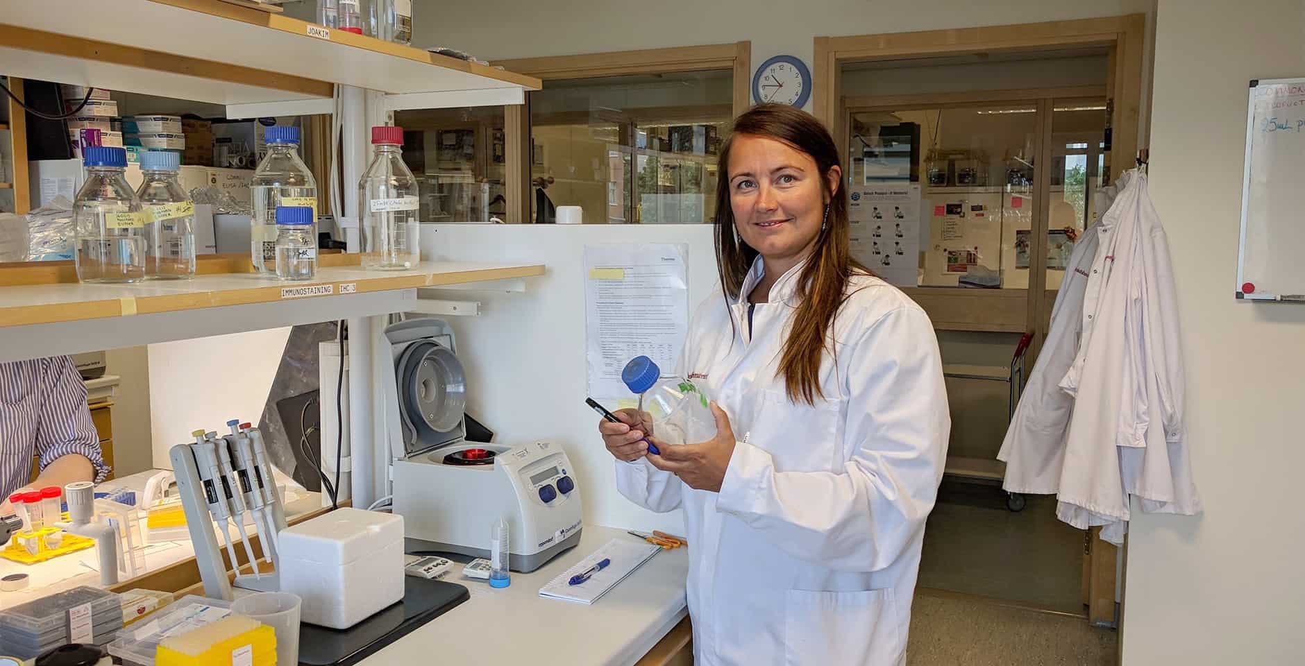 Porträtt av Stina Syvänen som står i ett labb.