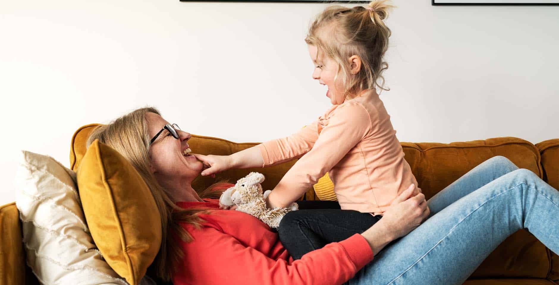 Mamma leker med sin dotter i en soffa.