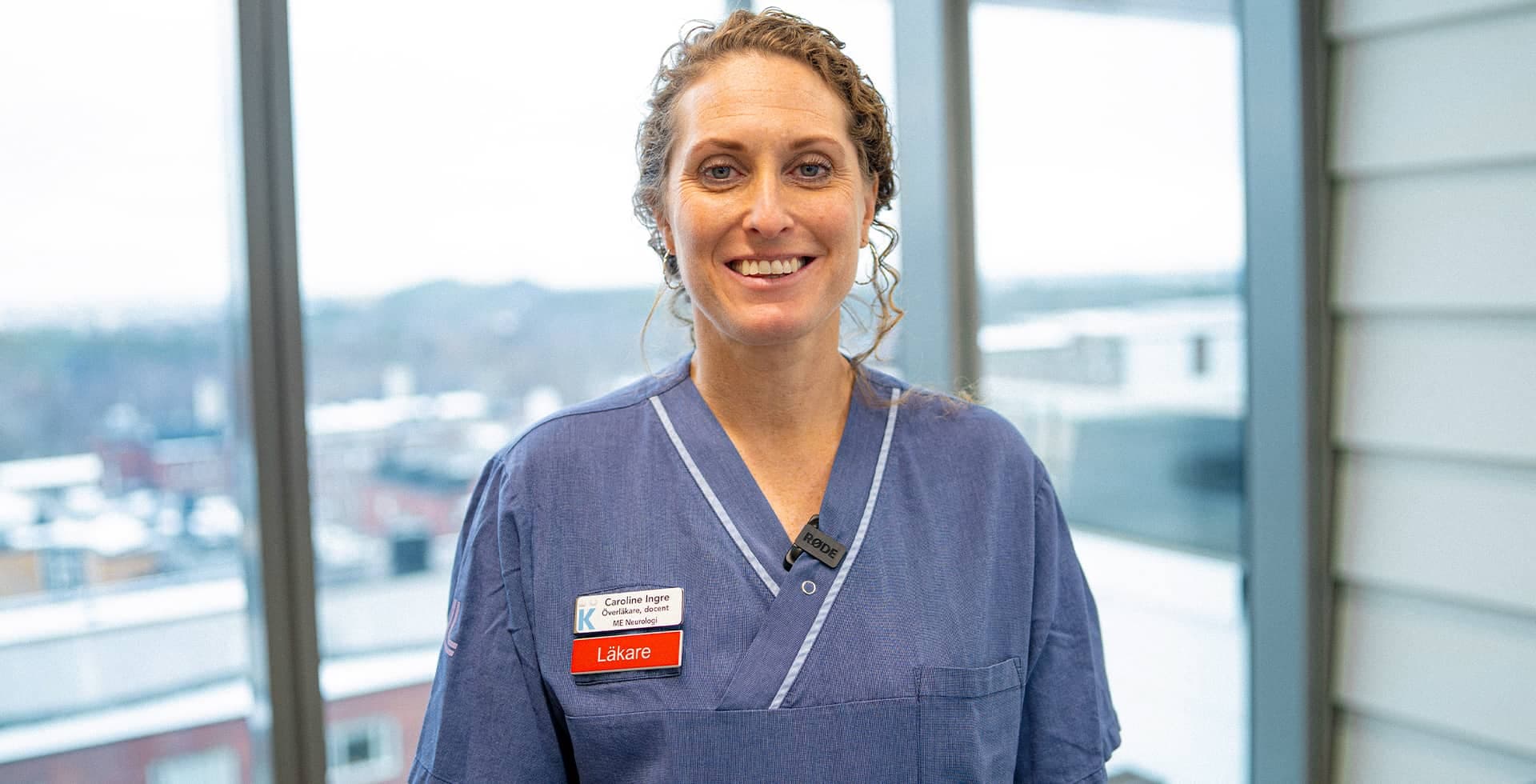 Porträtt på läkaren och hjärnforskaren Caroline Ingre iklädd en blå läkarrock.