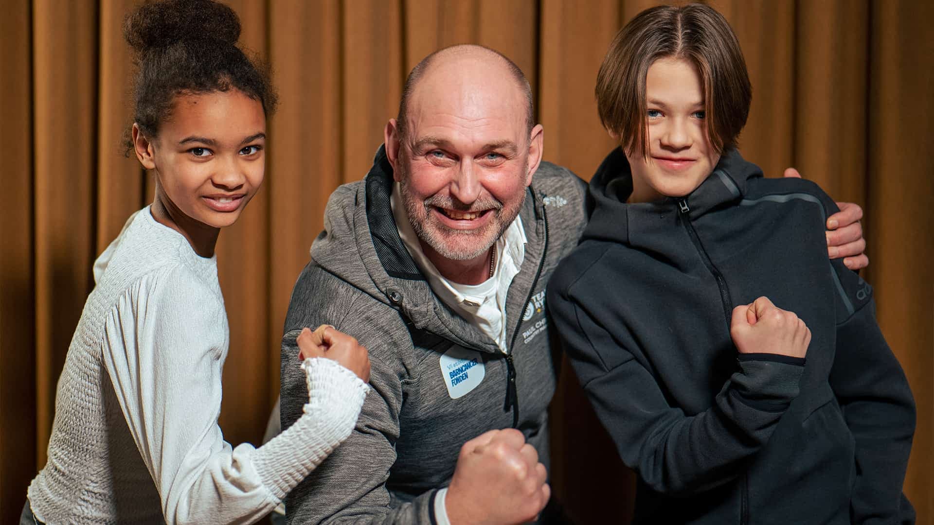 Paul Chronqvist Svensson som är Country Manager för Team Rynkeby står med två barn och spänner armarna, tittandes in i kameran.