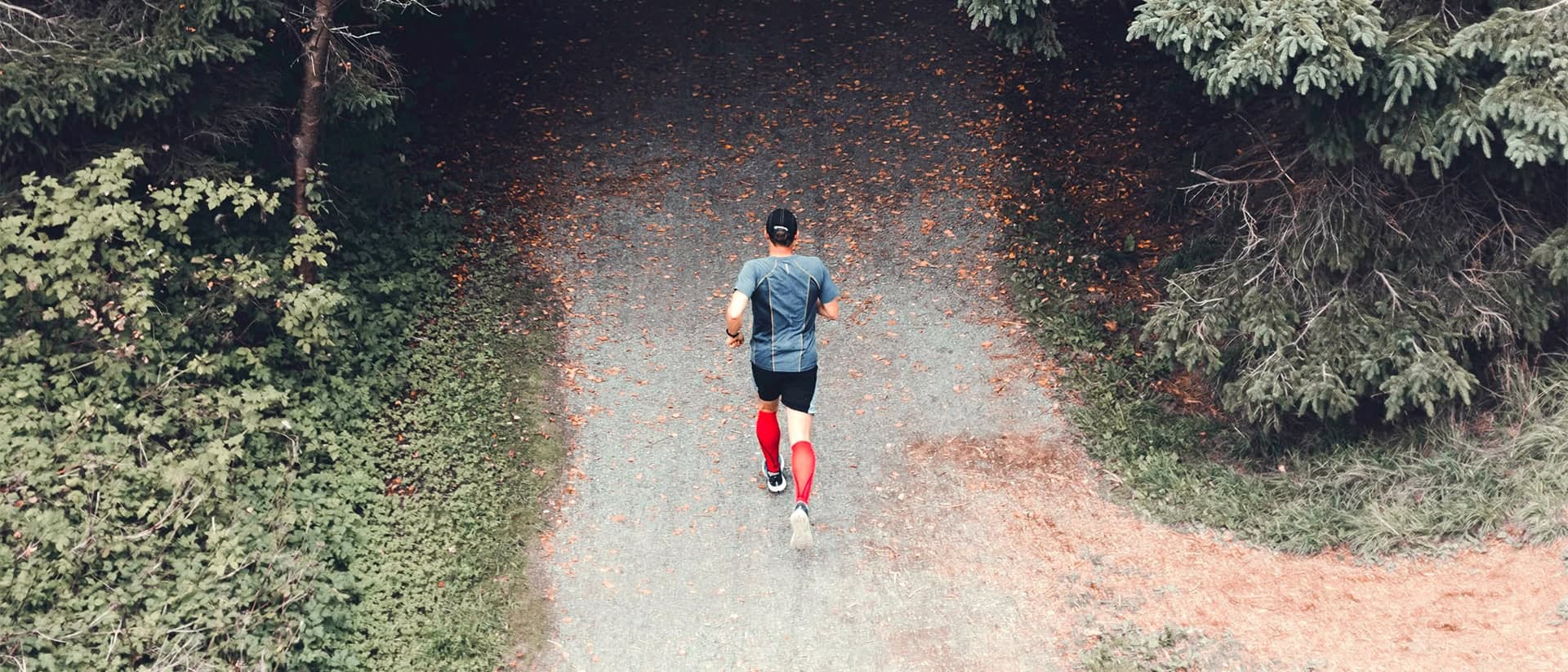 Person som springer på väg som leder in i en skog.