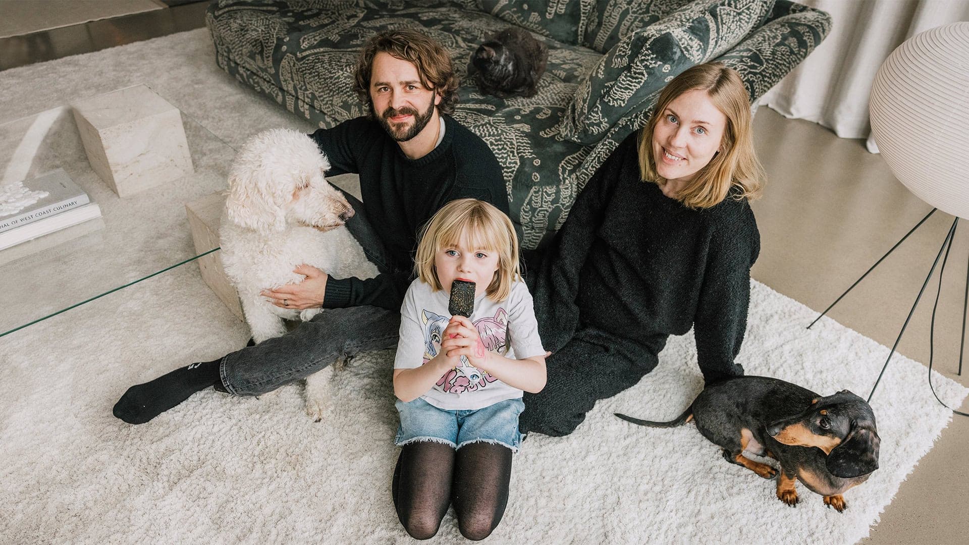 Porträtt av Familjen Svanfeldt som sitter på golvet med deras hundar och katt.