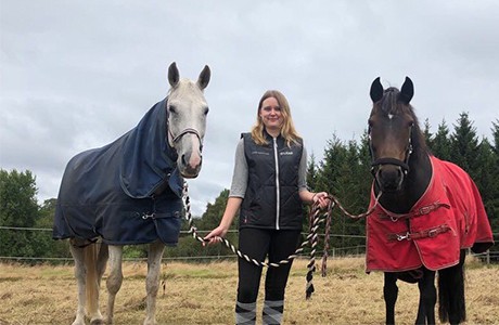 Therese står mellan två hästar.